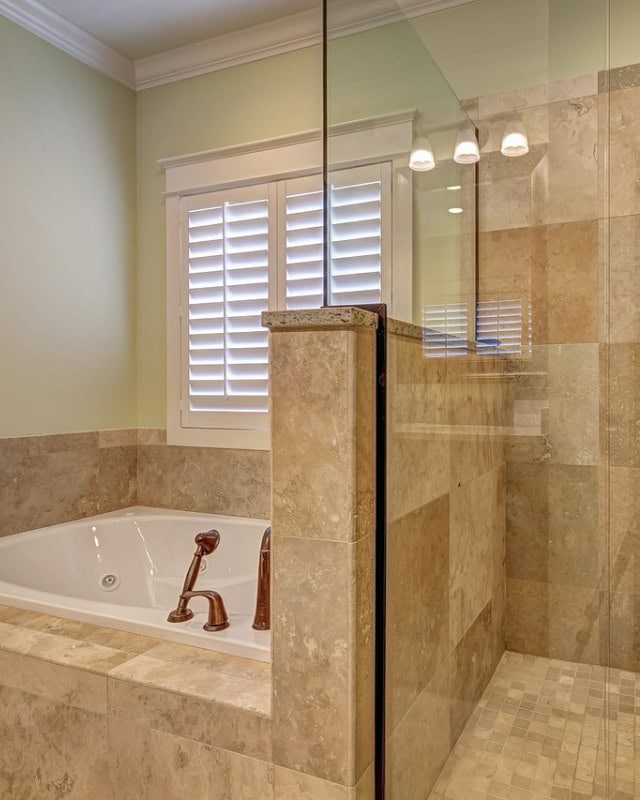 A modern bathroom with a glass shower door and a bathtub.