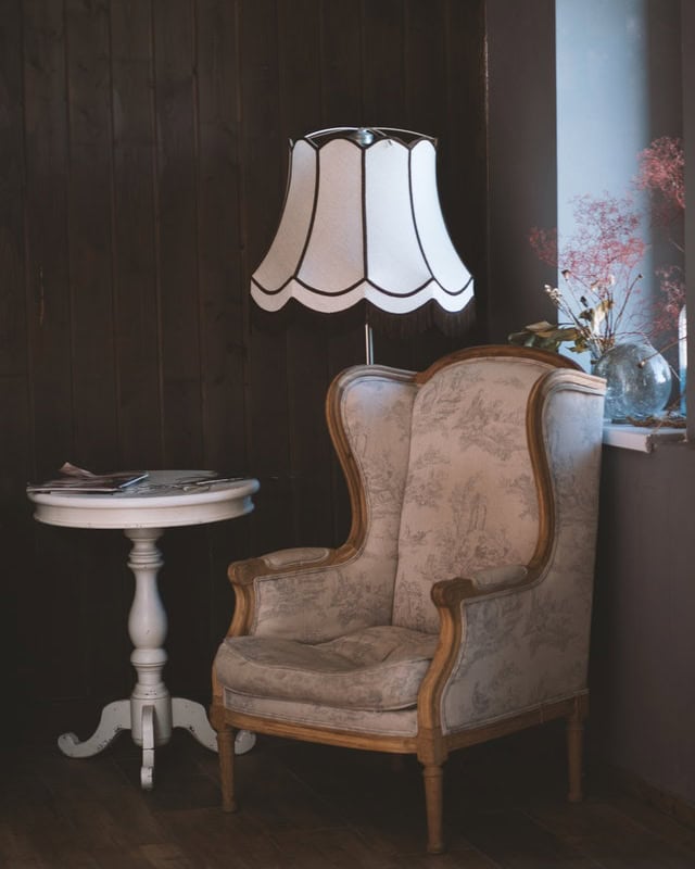 A well-lit room with a chair, lamp, and table.